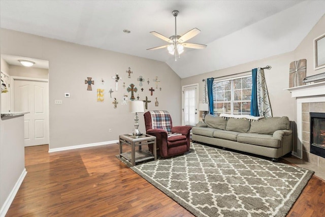 living room with hardwood / wood-style flooring, vaulted ceiling, ceiling fan, and a fireplace