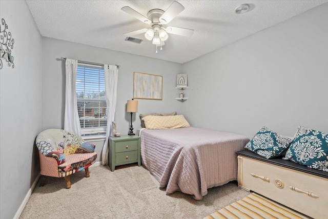 bedroom featuring ceiling fan, light colored carpet, and a textured ceiling