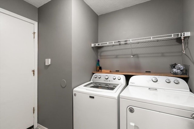 clothes washing area with a textured ceiling and washer and clothes dryer