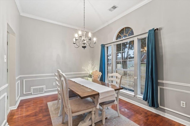 dining area with dark hardwood / wood-style flooring, crown molding, and a chandelier