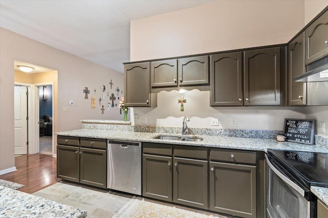 kitchen with sink, stainless steel appliances, light hardwood / wood-style floors, and light stone countertops