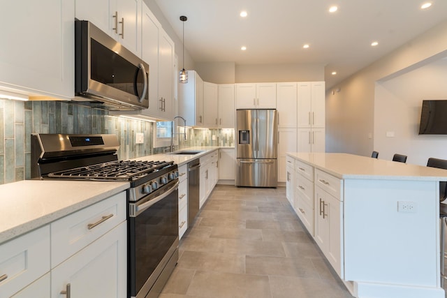 kitchen featuring sink, a breakfast bar area, appliances with stainless steel finishes, backsplash, and white cabinets