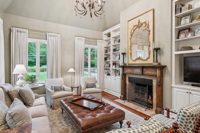 living room featuring lofted ceiling, built in shelves, a tile fireplace, and a chandelier