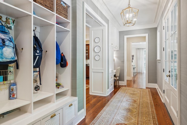 mudroom with dark wood-type flooring, ornamental molding, and a notable chandelier