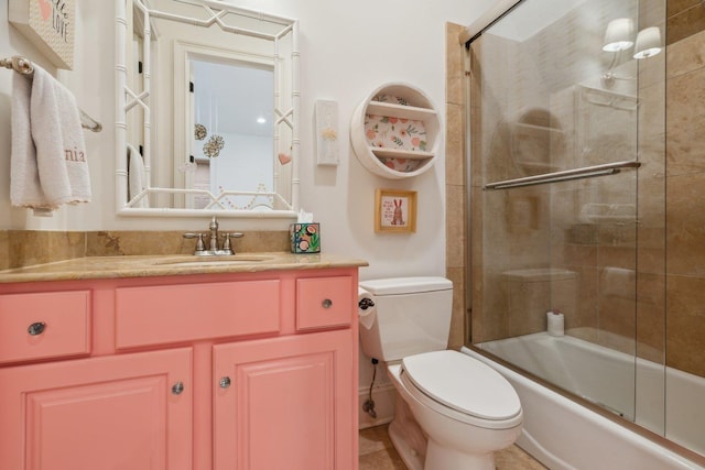 full bathroom featuring vanity, combined bath / shower with glass door, and toilet