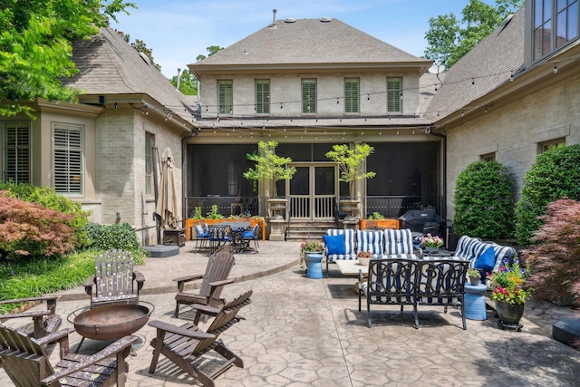 view of patio / terrace featuring a grill, an outdoor living space with a fire pit, and a sunroom