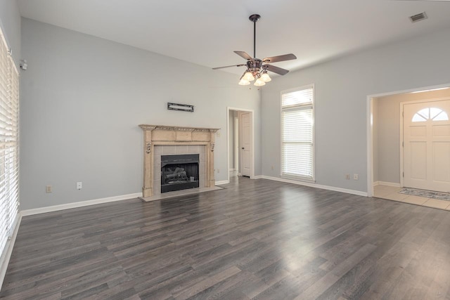 unfurnished living room featuring ceiling fan, dark hardwood / wood-style flooring, and a tile fireplace