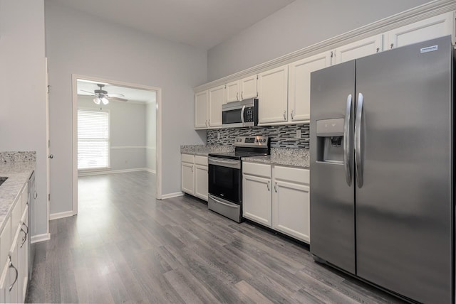 kitchen featuring white cabinetry, appliances with stainless steel finishes, hardwood / wood-style flooring, light stone countertops, and backsplash