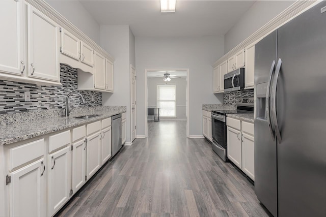 kitchen with sink, white cabinetry, dark hardwood / wood-style flooring, stainless steel appliances, and light stone countertops