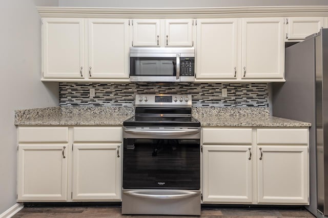 kitchen featuring stainless steel appliances, light stone countertops, white cabinets, and decorative backsplash