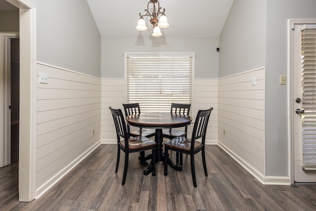 dining area with a chandelier, wooden walls, and dark hardwood / wood-style flooring