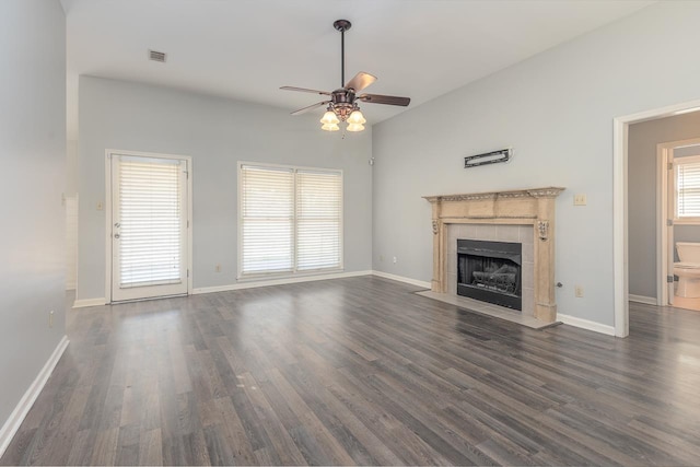 unfurnished living room featuring ceiling fan, dark hardwood / wood-style floors, and a tile fireplace