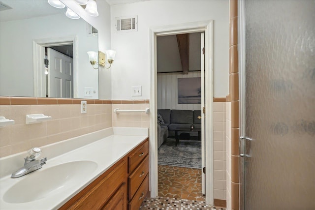 bathroom featuring walk in shower, vanity, a chandelier, and tile walls