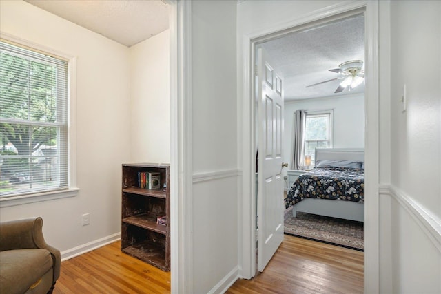 living area featuring ceiling fan, a textured ceiling, and light hardwood / wood-style flooring