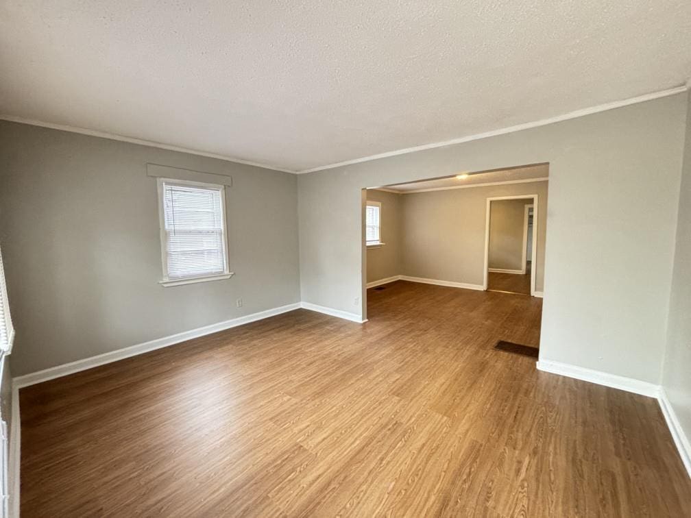 unfurnished room with hardwood / wood-style flooring, ornamental molding, and a textured ceiling