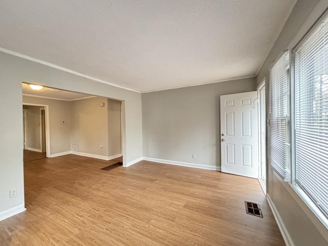 empty room with crown molding, light hardwood / wood-style flooring, and a textured ceiling