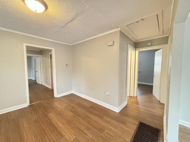 spare room featuring crown molding, wood-type flooring, and a textured ceiling