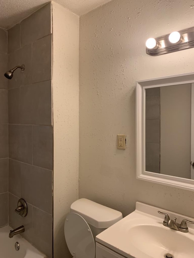 full bathroom featuring tiled shower / bath combo, vanity, a textured ceiling, and toilet