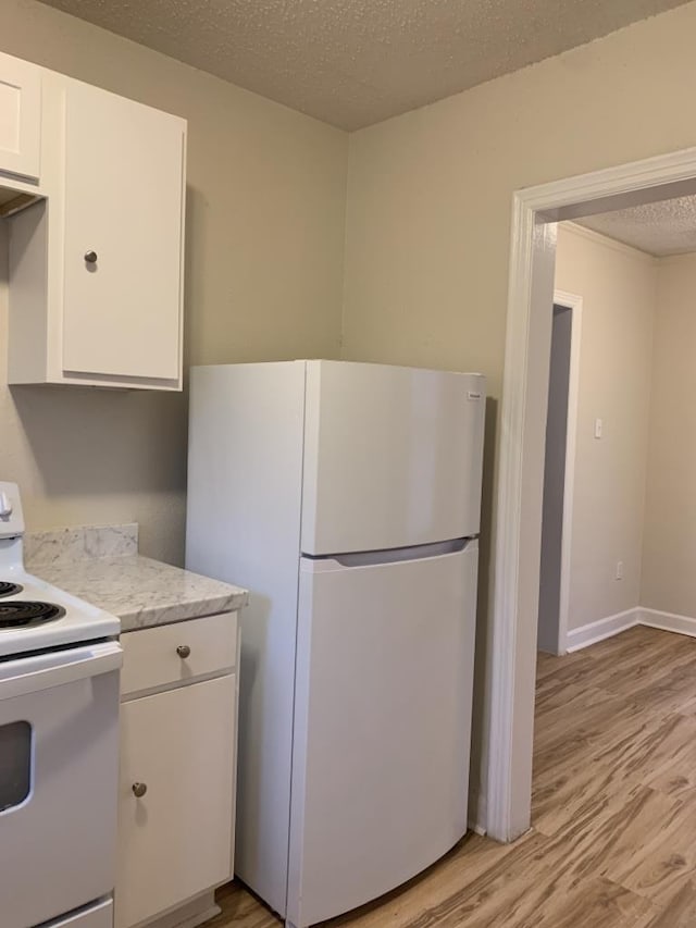 kitchen featuring white cabinetry, light stone counters, a textured ceiling, light wood-type flooring, and white appliances