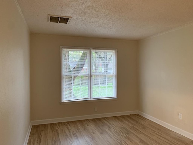 spare room with a textured ceiling and light hardwood / wood-style floors