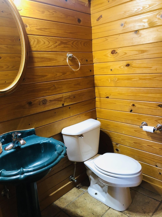 bathroom with toilet and wood walls