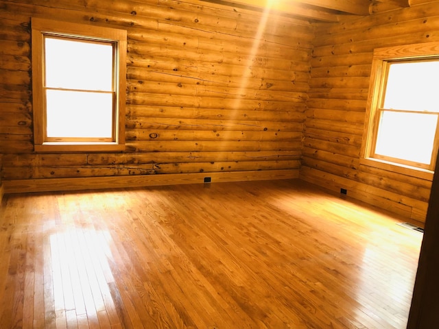 empty room with rustic walls, light wood-style flooring, and visible vents