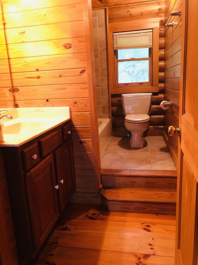 bathroom with vanity, toilet, and wood walls