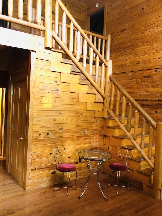 stairway featuring a towering ceiling, wood-type flooring, and wood walls