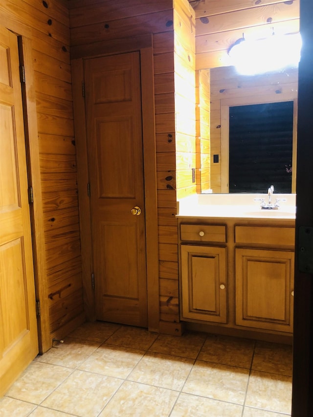 bathroom with tile patterned flooring, a sink, and wooden walls