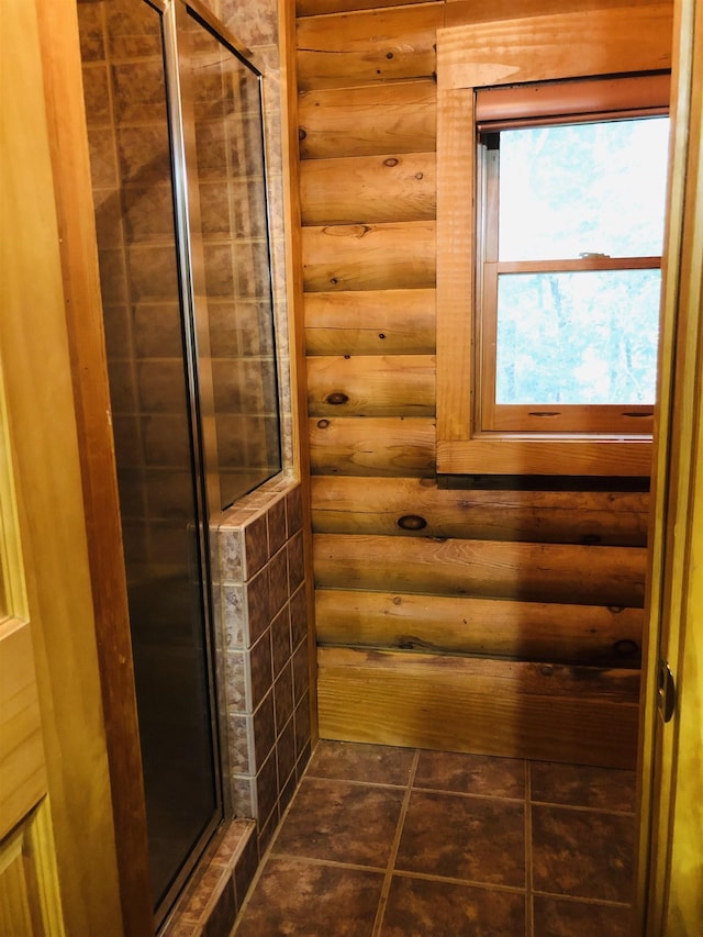 bathroom featuring tile patterned flooring, log walls, and a shower with door