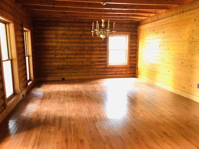 unfurnished room featuring beamed ceiling, wood-type flooring, and a chandelier