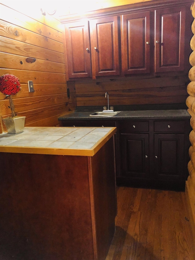 kitchen featuring wooden walls, dark hardwood / wood-style floors, and sink