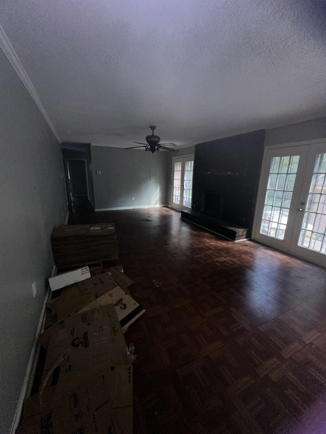 unfurnished living room featuring dark parquet flooring, ceiling fan, a textured ceiling, and french doors