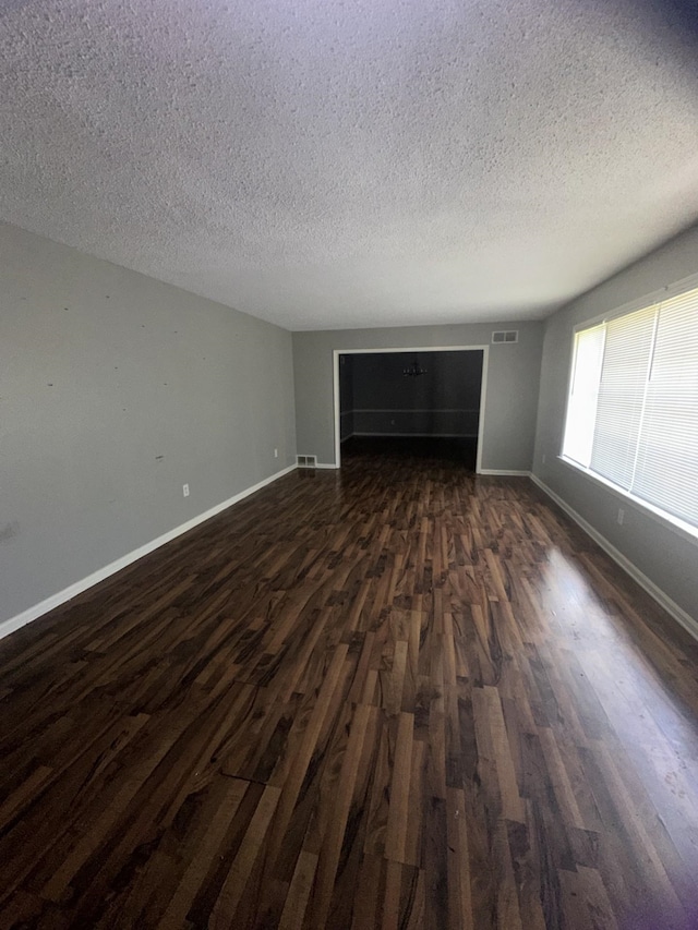 spare room featuring dark wood-type flooring and a textured ceiling