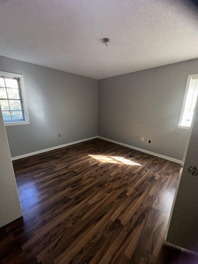 empty room with dark hardwood / wood-style floors and a textured ceiling