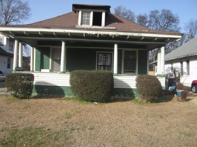 rear view of house with a yard and a porch