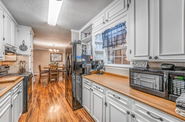 kitchen featuring pendant lighting, white cabinets, hardwood / wood-style floors, and black appliances