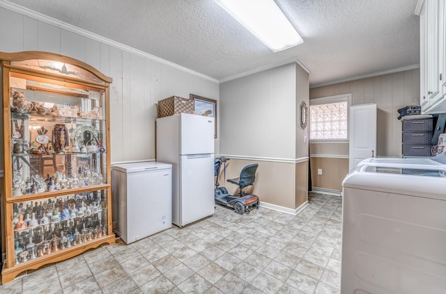 laundry room featuring ornamental molding, washing machine and clothes dryer, and a textured ceiling