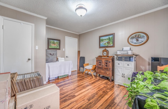 interior space with wood-type flooring, a textured ceiling, and crown molding