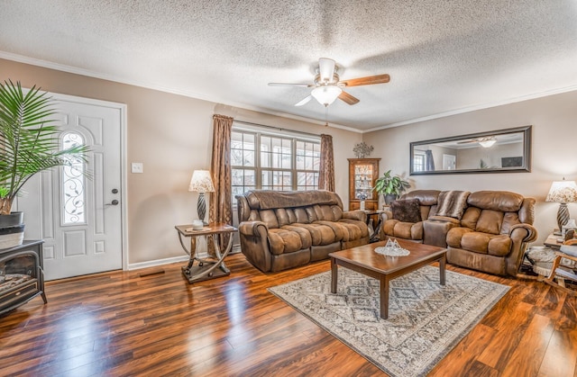 living room featuring a wood stove, ornamental molding, ceiling fan, dark wood-type flooring, and a textured ceiling