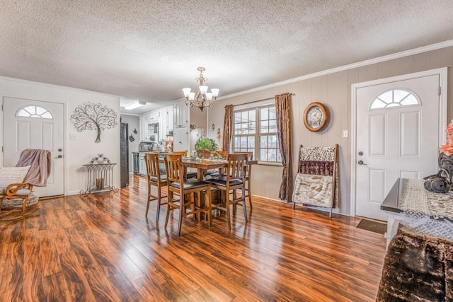 dining area with an inviting chandelier, hardwood / wood-style flooring, ornamental molding, and a textured ceiling