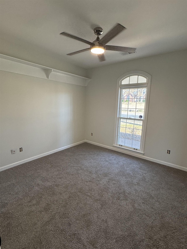 spare room with dark carpet and ceiling fan