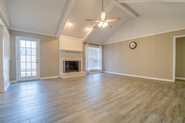 unfurnished living room featuring vaulted ceiling with beams, ceiling fan, a brick fireplace, and light wood-type flooring