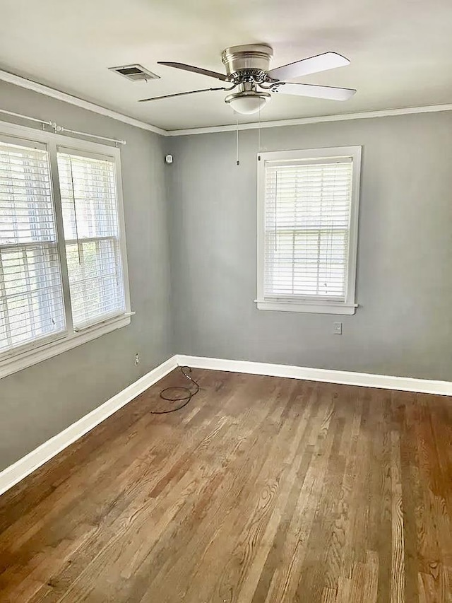 unfurnished room with a wealth of natural light, wood-type flooring, and ornamental molding