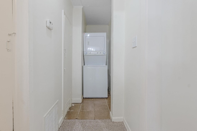 hallway with light tile patterned flooring and stacked washer / drying machine