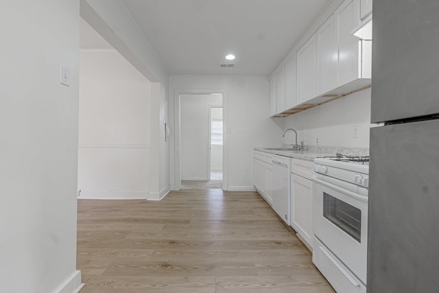 kitchen with white cabinetry, sink, white appliances, and light hardwood / wood-style flooring