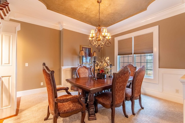 dining space featuring a tray ceiling, ornamental molding, light colored carpet, and a chandelier