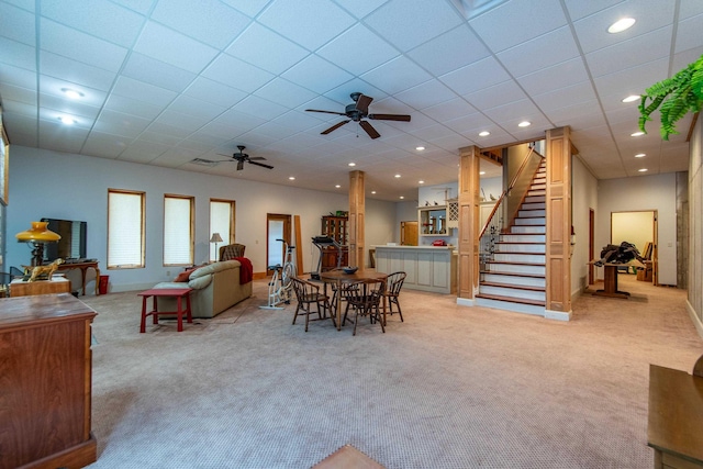 dining room with light carpet, a drop ceiling, and ceiling fan