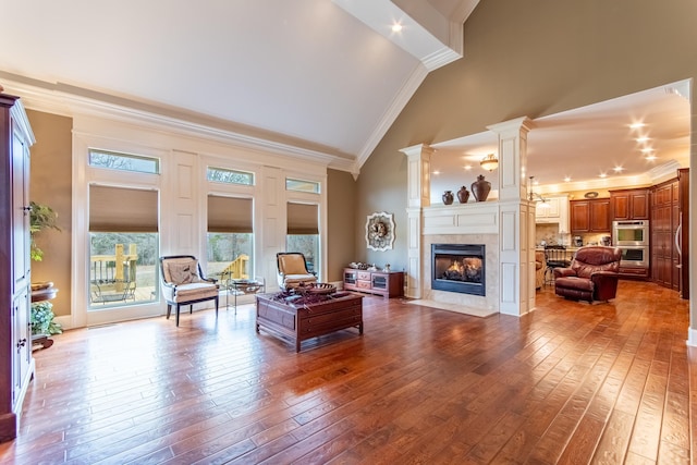 living room featuring high vaulted ceiling, ornamental molding, decorative columns, and hardwood / wood-style floors