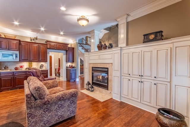 living room featuring hardwood / wood-style flooring, ornamental molding, decorative columns, and a fireplace